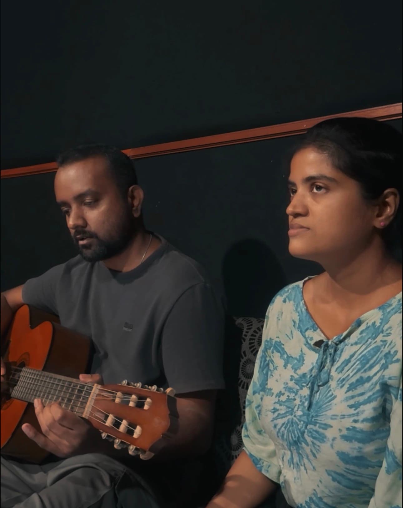 A guitarist and vocalist seated together during an intimate acoustic rehearsal inside the Tastic Wavs studio.