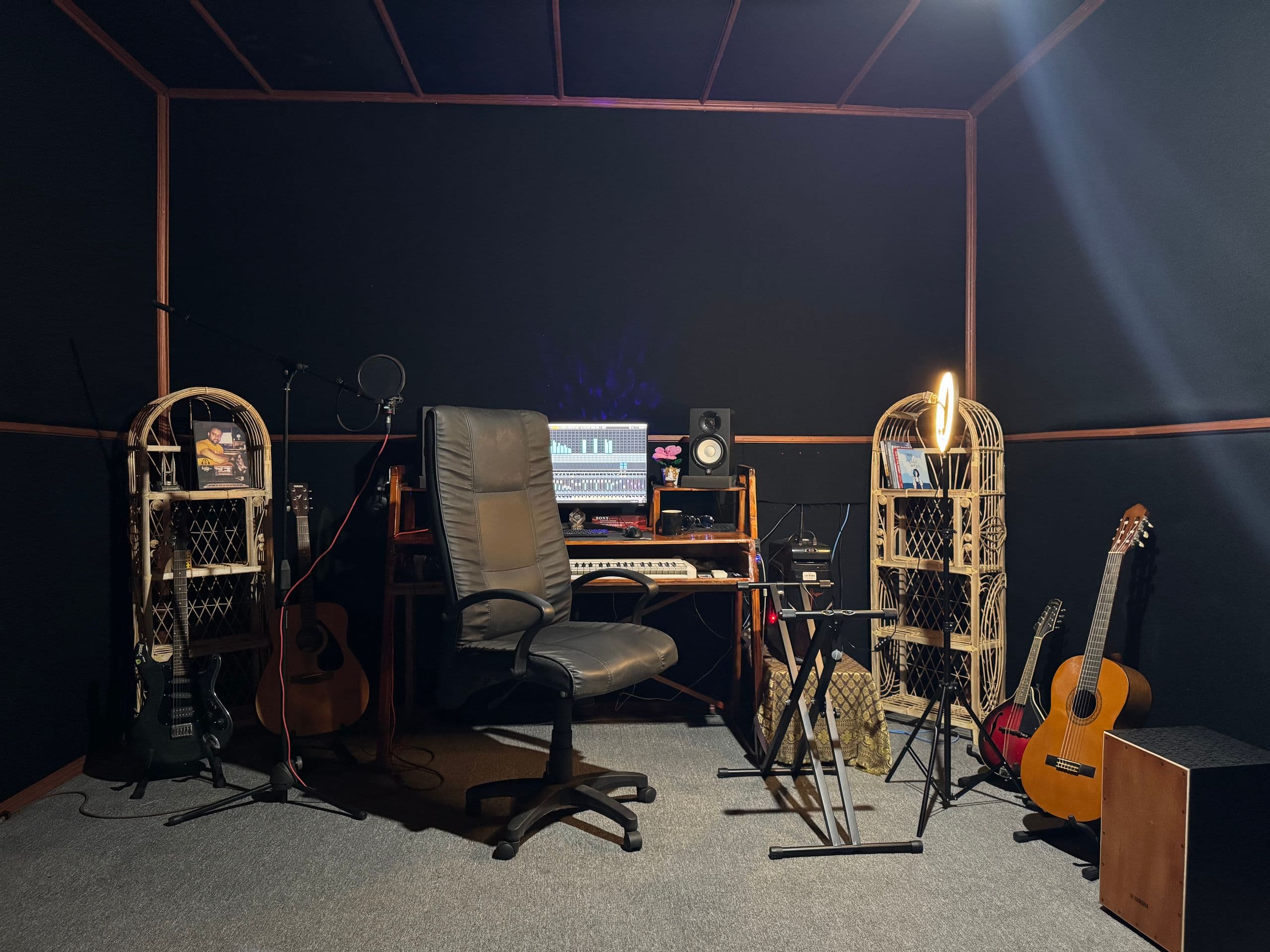 Wide shot of the Tastic Wavs studio room with workstation, microphones, instruments, and seating.